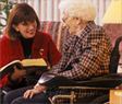 Woman reading to a woman in a wheelchair