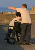 Man behind woman in wheelchair